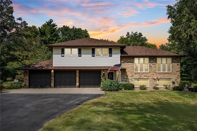 tri-level home featuring a garage and a lawn