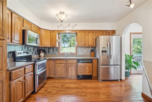 kitchen with backsplash, plenty of natural light, stainless steel appliances, and hardwood / wood-style flooring