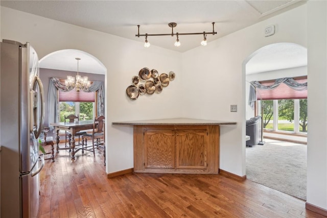 kitchen with stainless steel fridge, light wood-type flooring, decorative light fixtures, and an inviting chandelier