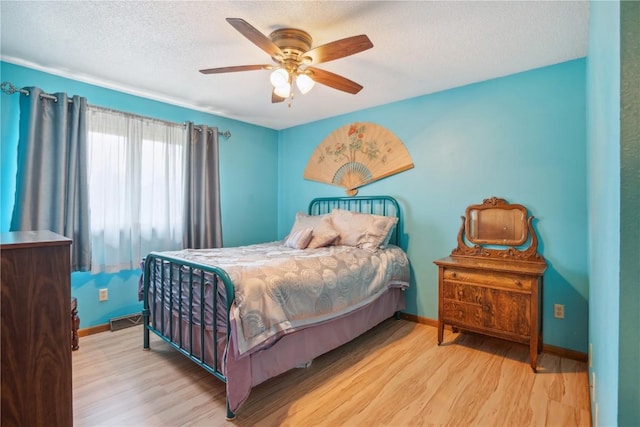 bedroom with ceiling fan, a textured ceiling, and light hardwood / wood-style flooring