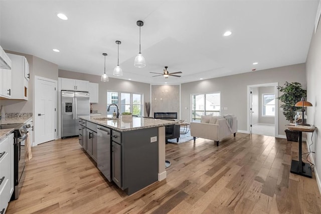 kitchen with a center island with sink, white cabinets, light hardwood / wood-style flooring, and appliances with stainless steel finishes