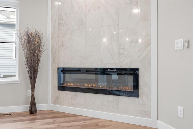 room details featuring a tiled fireplace and hardwood / wood-style flooring