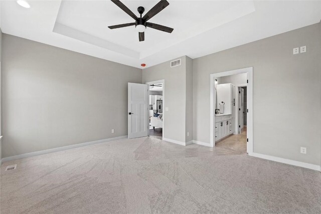1596 Connection Ave, Marion, IA 52302 - unfurnished bedroom with a raised ceiling, light carpet, baseboards, ensuite bathroom, and ceiling fan