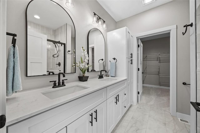 1596 Connection Ave, Marion, IA 52302 - bathroom featuring marble finish floors, a shower stall, double vanity, a walk in closet, and baseboards
