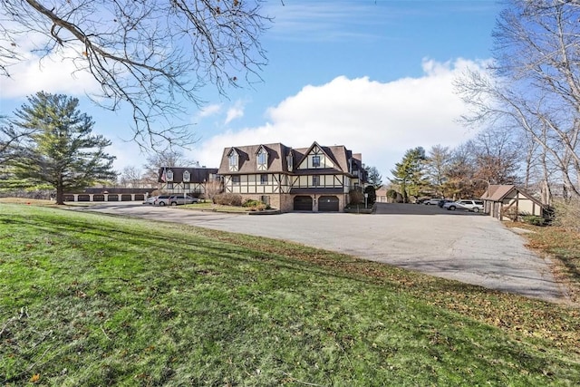 english style home featuring a front lawn and a garage