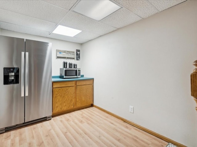 kitchen with appliances with stainless steel finishes, light wood-type flooring, and a drop ceiling