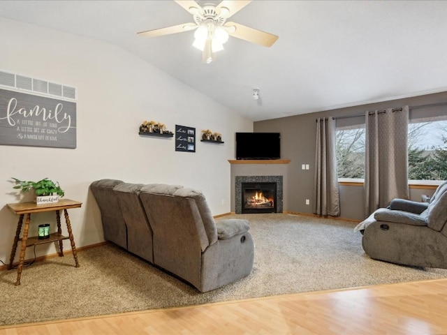 living room featuring a tile fireplace, ceiling fan, hardwood / wood-style floors, and vaulted ceiling