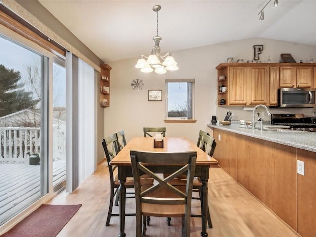 dining area featuring a chandelier, light hardwood / wood-style floors, vaulted ceiling, and sink