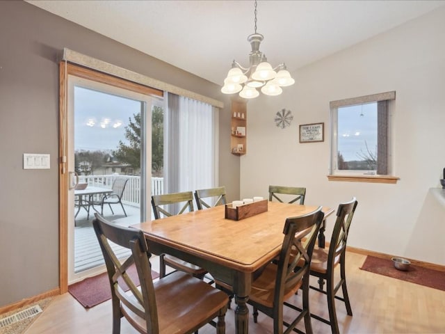 dining space featuring light hardwood / wood-style floors and a chandelier