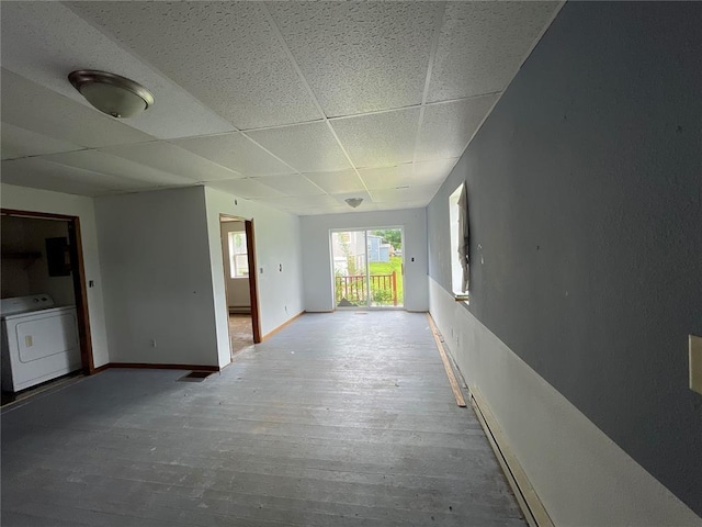 hall with a paneled ceiling, hardwood / wood-style floors, and washer / dryer