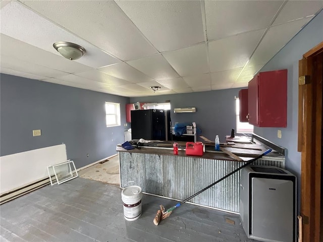 kitchen with hardwood / wood-style floors, a drop ceiling, and black refrigerator