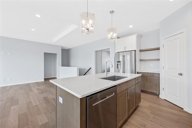 kitchen with appliances with stainless steel finishes, a center island with sink, light hardwood / wood-style flooring, and sink