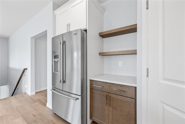 kitchen with white cabinets, stainless steel fridge with ice dispenser, and light hardwood / wood-style flooring