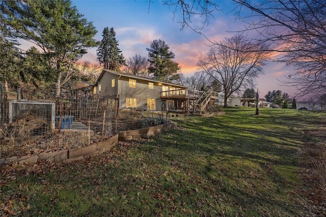 property exterior at dusk featuring a deck, a garden, a yard, and stairway