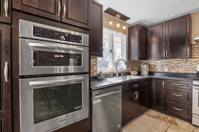 kitchen featuring tasteful backsplash, dark countertops, appliances with stainless steel finishes, dark brown cabinets, and a sink