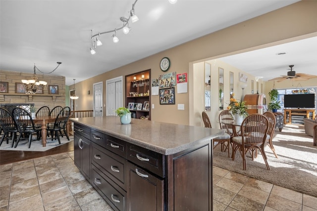 kitchen with open floor plan, a center island, rail lighting, dark brown cabinets, and ceiling fan with notable chandelier