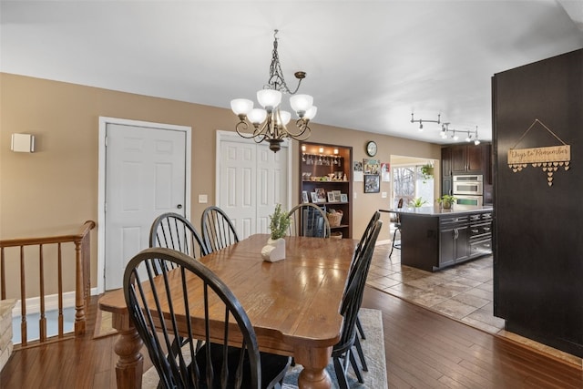 dining room with baseboards, wood-type flooring, and an inviting chandelier