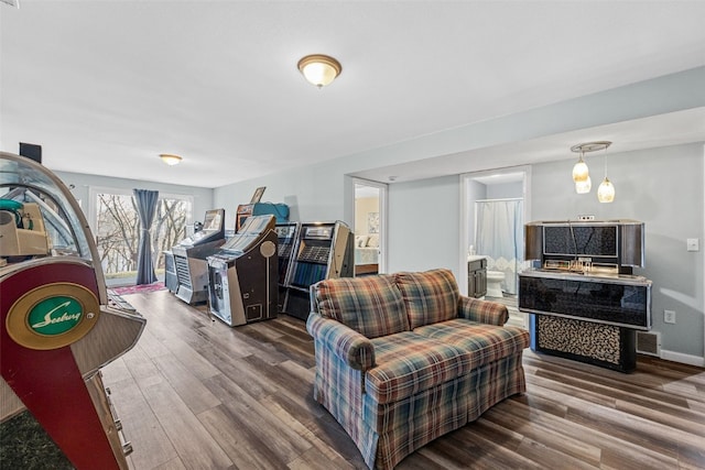 living room with wood finished floors, visible vents, and baseboards