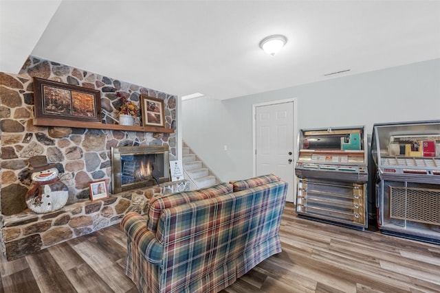 living room featuring stairs, visible vents, a fireplace, and wood finished floors