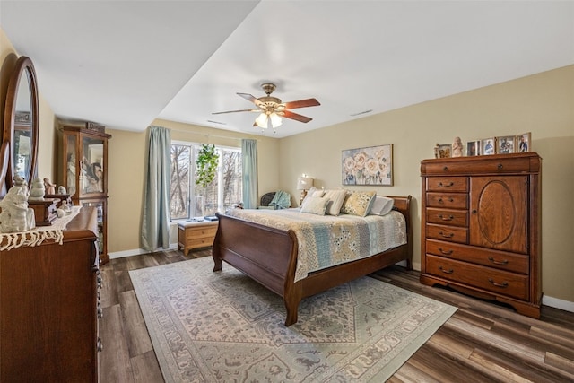 bedroom with dark wood-style flooring, visible vents, ceiling fan, and baseboards