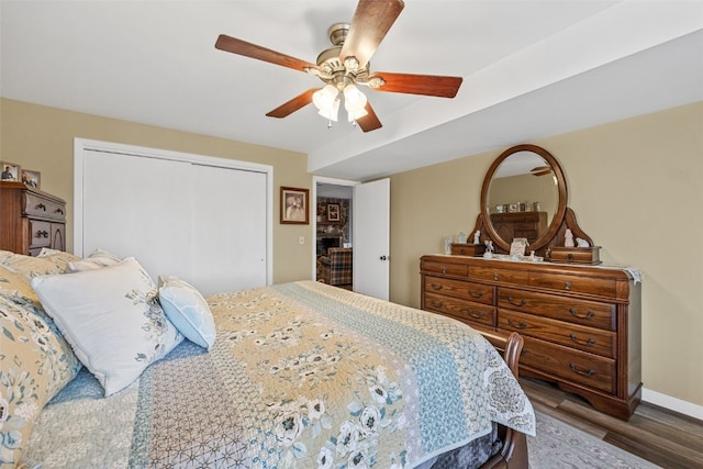 bedroom with a closet, wood finished floors, a ceiling fan, and baseboards