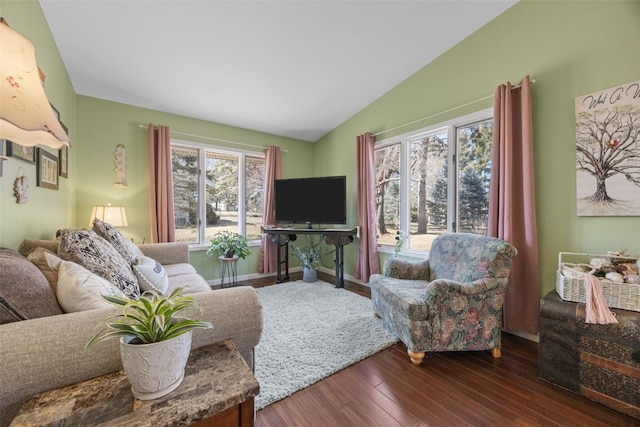 living room featuring vaulted ceiling, baseboards, and wood finished floors