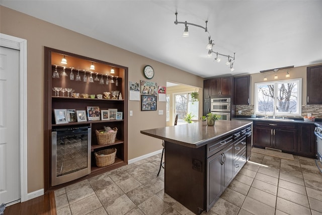 kitchen with tasteful backsplash, dark countertops, a sink, and dark brown cabinetry