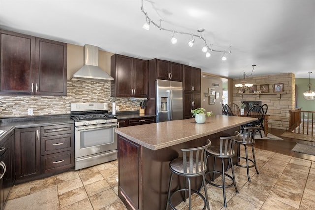 kitchen with a breakfast bar area, stainless steel appliances, a kitchen island, wall chimney range hood, and decorative backsplash