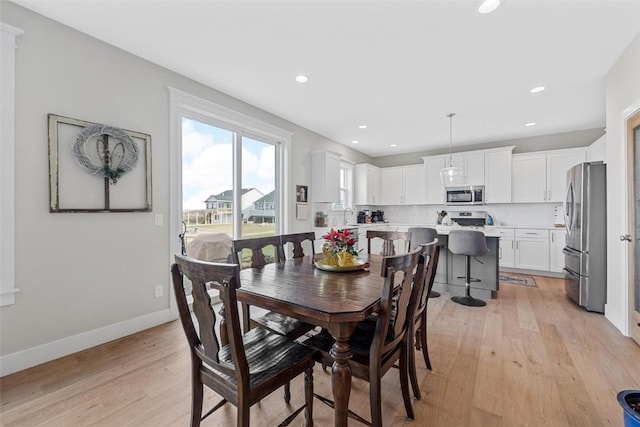 dining area with sink and light wood-type flooring