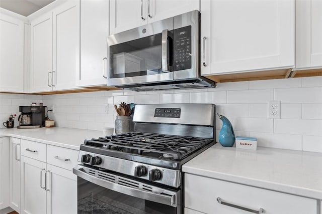 kitchen featuring decorative backsplash, white cabinets, and appliances with stainless steel finishes