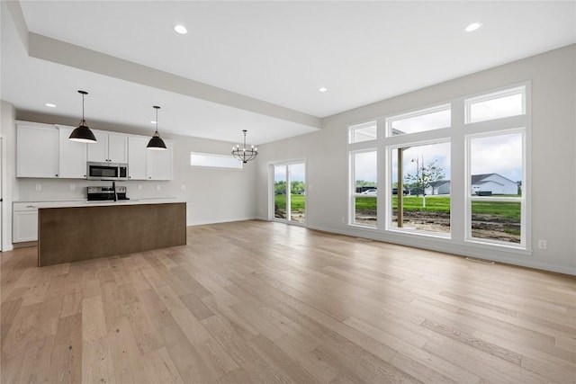 unfurnished living room featuring a notable chandelier and light hardwood / wood-style flooring