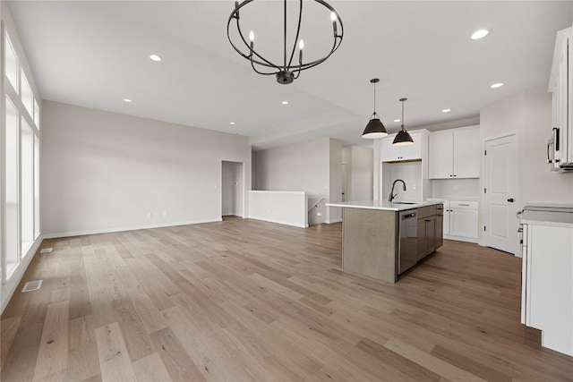 kitchen featuring white cabinets, a notable chandelier, hanging light fixtures, and an island with sink