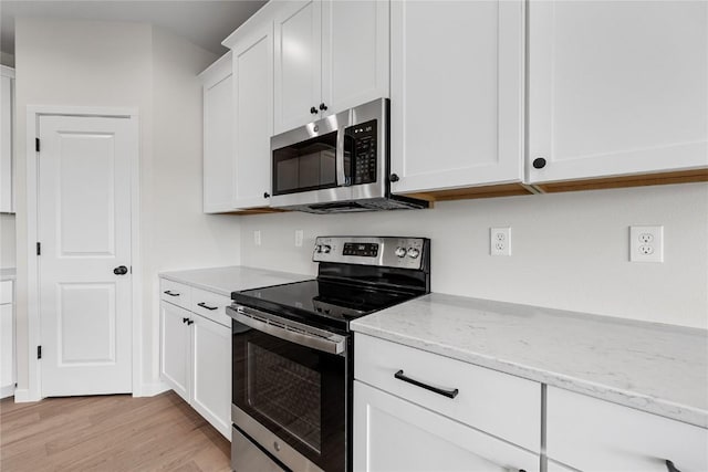 kitchen with white cabinets, stainless steel appliances, light hardwood / wood-style flooring, and light stone countertops