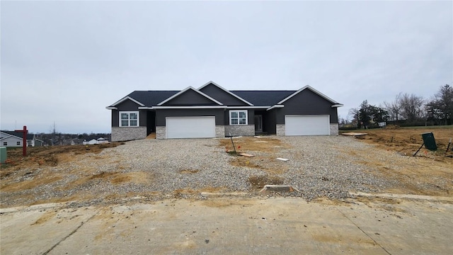 view of front facade with a garage, gravel driveway, and stone siding