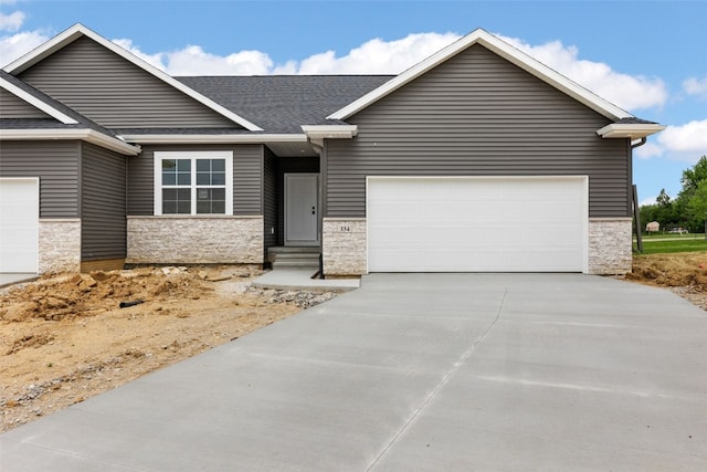 334 Quiver Ct, Marion, IA 52302 - view of front facade with stone siding, an attached garage, driveway, and a shingled roof