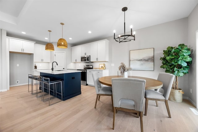 334 Quiver Ct, Marion, IA 52302 - kitchen with appliances with stainless steel finishes, an island with sink, white cabinets, a chandelier, and light wood-style flooring