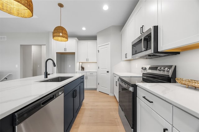 334 Quiver Ct, Marion, IA 52302 - kitchen with appliances with stainless steel finishes, a sink, light wood-style flooring, white cabinetry, and decorative light fixtures