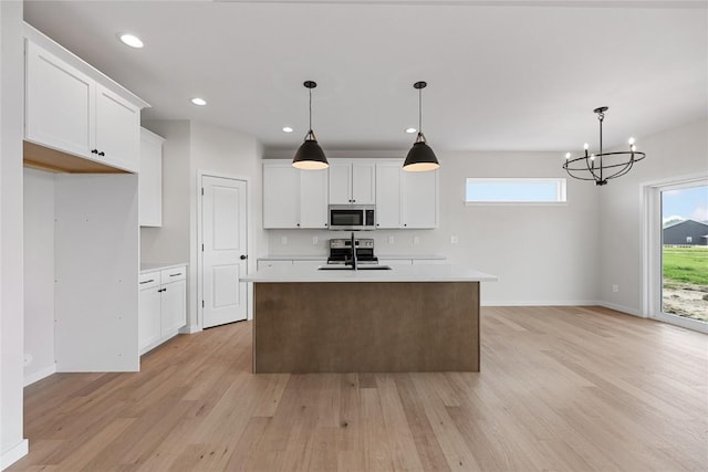 kitchen featuring white cabinetry, appliances with stainless steel finishes, an island with sink, and hanging light fixtures