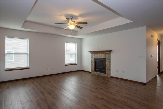 unfurnished living room featuring dark hardwood / wood-style floors, ceiling fan, a raised ceiling, and a fireplace