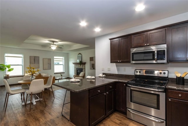 1135 Redbud Ave, Tiffin, IA 52340 - kitchen featuring appliances with stainless steel finishes, dark wood-style floors, dark brown cabinetry, a raised ceiling, and ceiling fan
