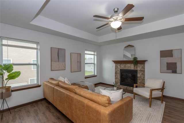 1135 Redbud Ave, Tiffin, IA 52340 - living area with a tray ceiling, a tile fireplace, a ceiling fan, wood finished floors, and baseboards