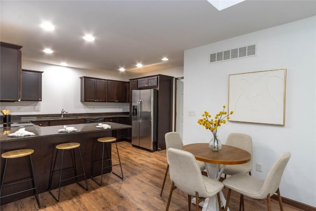 1135 Redbud Ave, Tiffin, IA 52340 - kitchen with stainless steel fridge with ice dispenser, a sink, a breakfast bar, dark brown cabinets, and light wood-type flooring