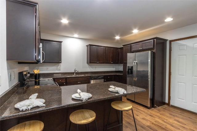 1135 Redbud Ave, Tiffin, IA 52340 - kitchen with stainless steel appliances, a sink, dark brown cabinetry, a peninsula, and light wood-style flooring