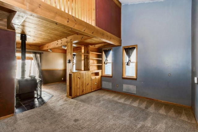 interior space with carpet floors, a wood stove, and wooden ceiling