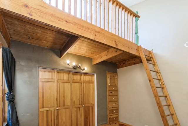 unfurnished bedroom featuring a closet, beamed ceiling, and wooden ceiling