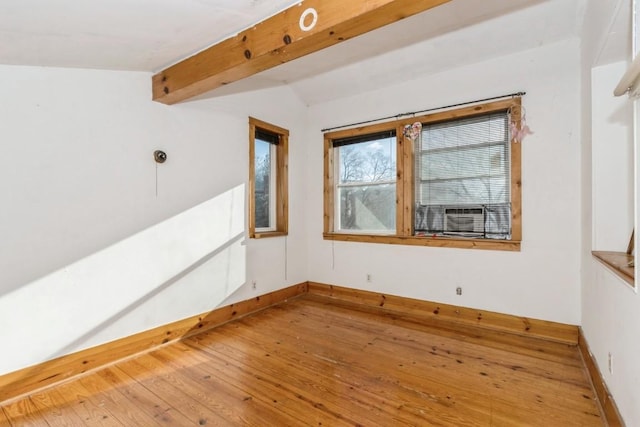 spare room featuring wood-type flooring and vaulted ceiling with beams