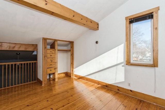 additional living space with vaulted ceiling with beams and wood-type flooring