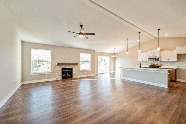 unfurnished living room featuring a healthy amount of sunlight, dark wood-type flooring, a ceiling fan, and lofted ceiling