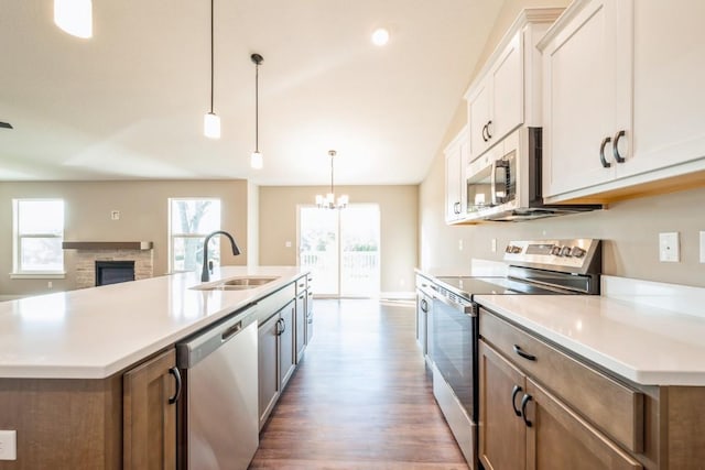 kitchen with sink, white cabinetry, pendant lighting, stainless steel appliances, and a kitchen island with sink