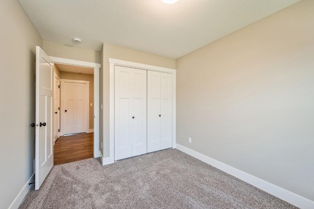 unfurnished bedroom with a closet, carpet flooring, and baseboards